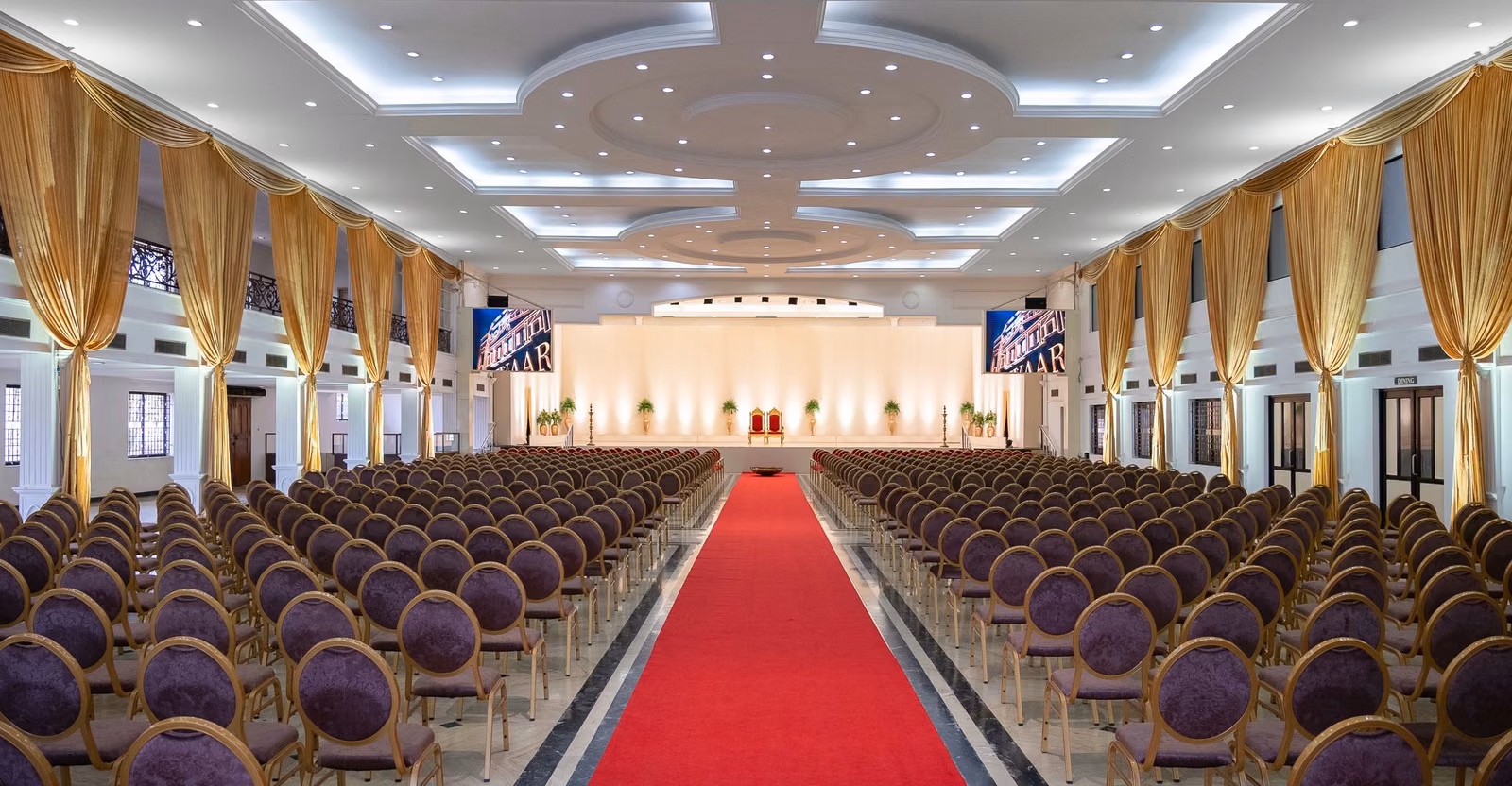 Shrivaaru Palace ballroom set for a ceremony with gold drapes and red carpet